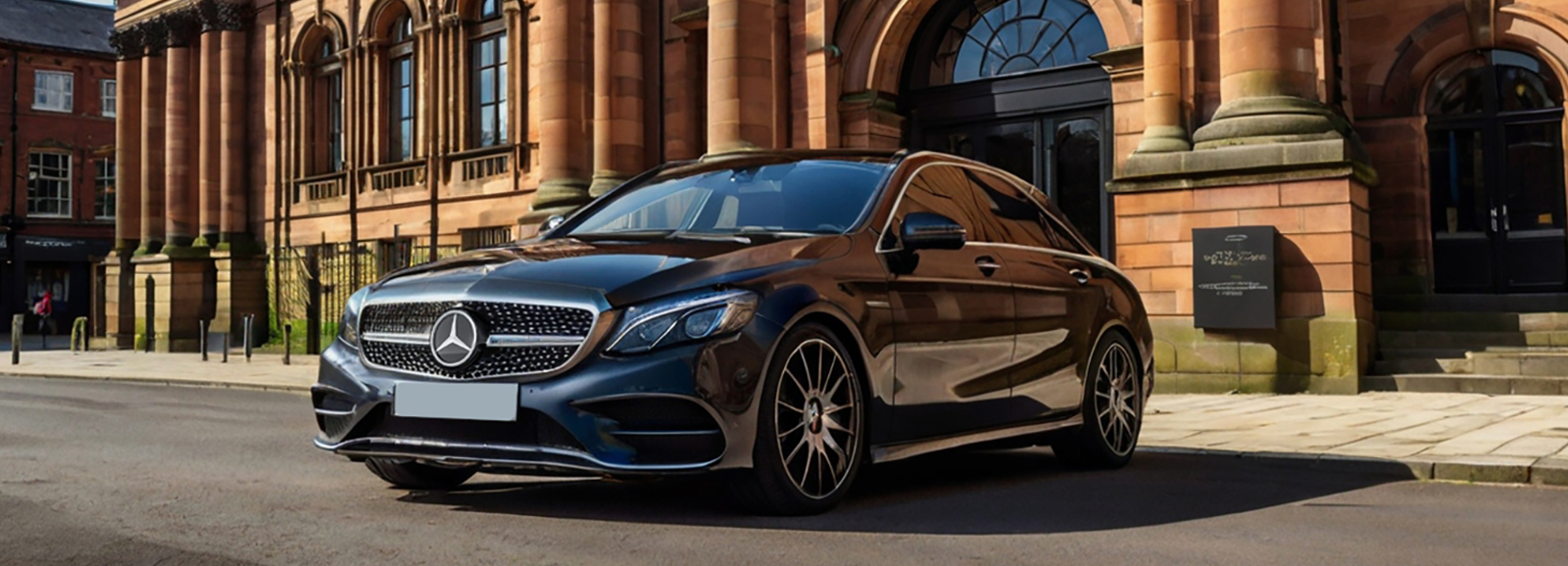 A Black Luxury Compact Executive Mercedes-Benz CLA car parked in front of a large building